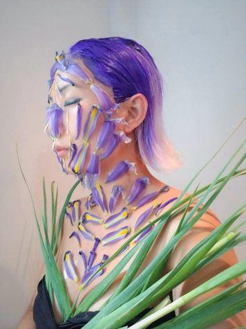 Blond Jenny covered in purple iris flower petals and leaves that match her short lavender hair 